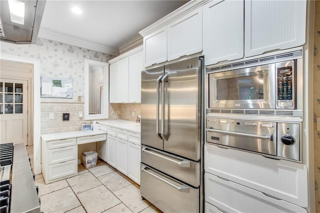 kitchen featuring crown molding, light countertops, appliances with stainless steel finishes, white cabinetry, and wallpapered walls