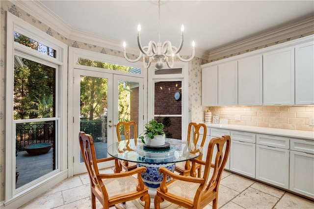 dining room with crown molding, a chandelier, stone tile flooring, and french doors