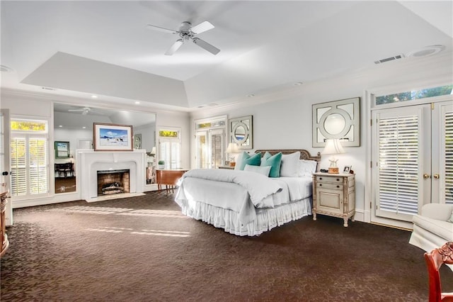 bedroom with a fireplace with flush hearth, visible vents, access to exterior, a tray ceiling, and dark carpet