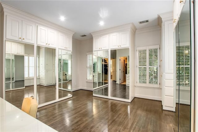 exercise room with a healthy amount of sunlight, visible vents, dark wood-style flooring, and crown molding