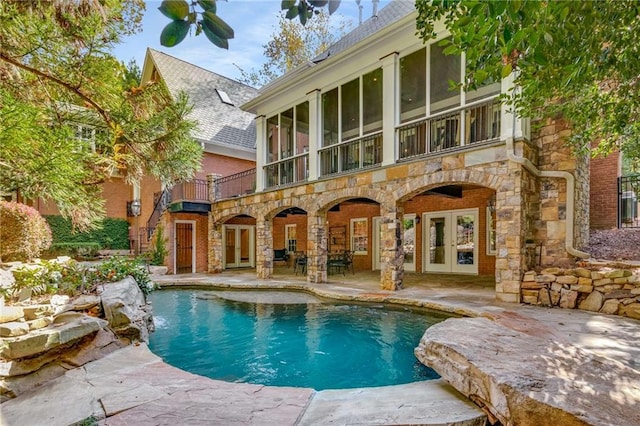 pool with french doors, a patio area, and a sunroom