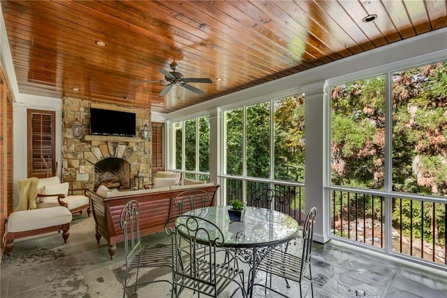 sunroom with a fireplace, wood ceiling, and a ceiling fan