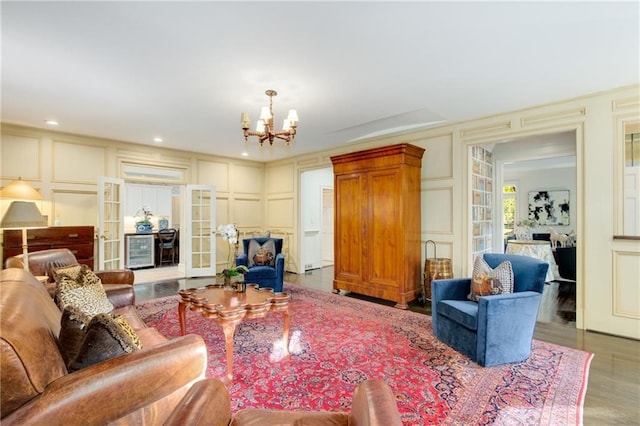 living area featuring wood finished floors, an inviting chandelier, french doors, a decorative wall, and recessed lighting