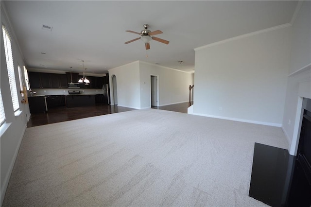 unfurnished living room featuring a fireplace with flush hearth, ornamental molding, arched walkways, baseboards, and ceiling fan