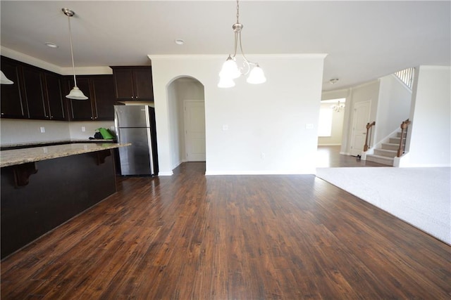 kitchen with a chandelier, open floor plan, dark wood finished floors, a breakfast bar area, and freestanding refrigerator