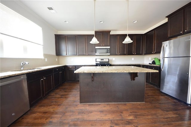 kitchen with dark brown cabinets, appliances with stainless steel finishes, a kitchen island, and a sink