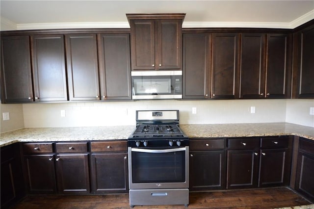 kitchen with dark brown cabinetry, backsplash, appliances with stainless steel finishes, and light stone counters