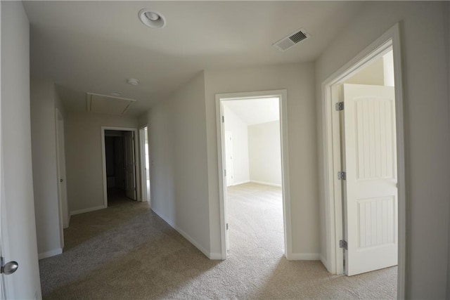 corridor with light carpet, visible vents, and baseboards