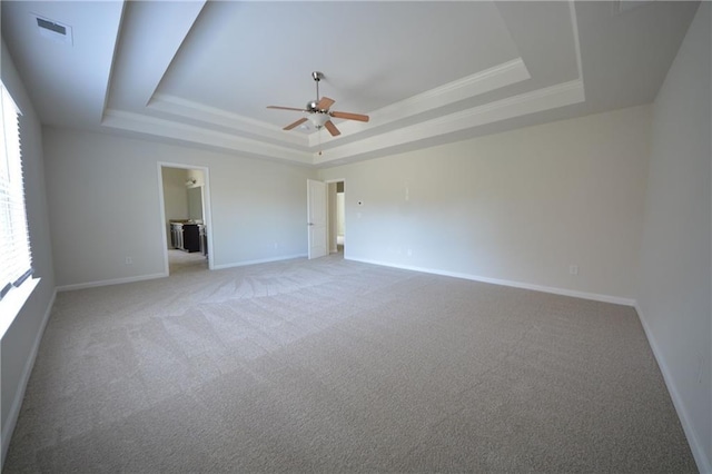 empty room featuring a raised ceiling, baseboards, and visible vents