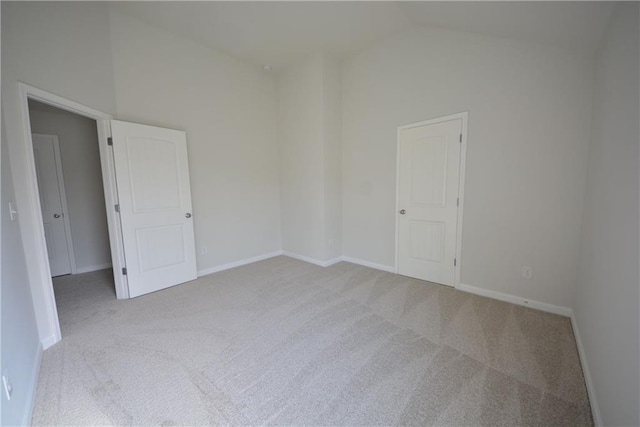 empty room with carpet flooring, baseboards, and high vaulted ceiling