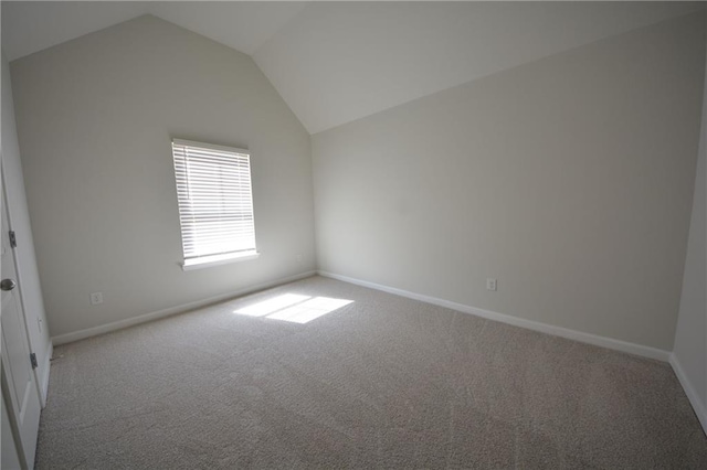 unfurnished room featuring carpet flooring, baseboards, and vaulted ceiling