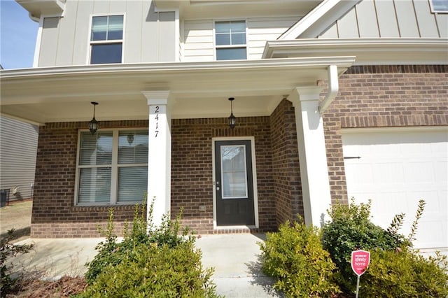 property entrance featuring covered porch, brick siding, and board and batten siding