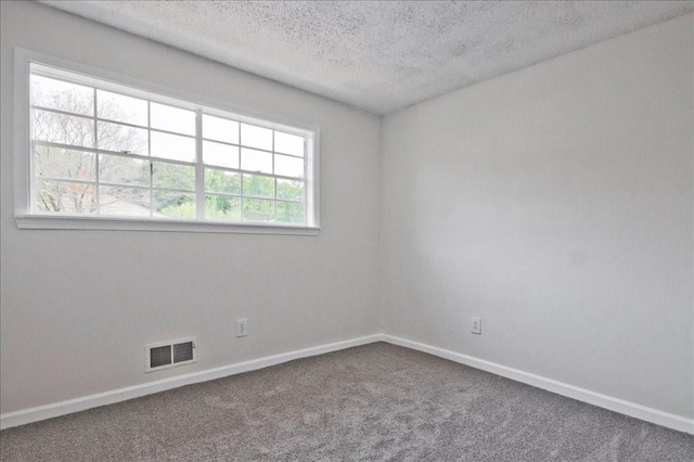 carpeted empty room with a textured ceiling, visible vents, and baseboards