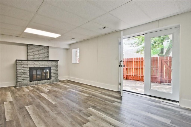 unfurnished living room featuring baseboards, a brick fireplace, wood finished floors, and visible vents