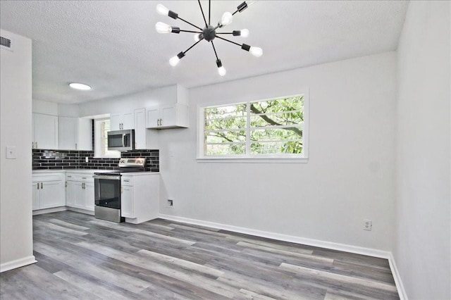 kitchen featuring plenty of natural light, white cabinetry, appliances with stainless steel finishes, and tasteful backsplash