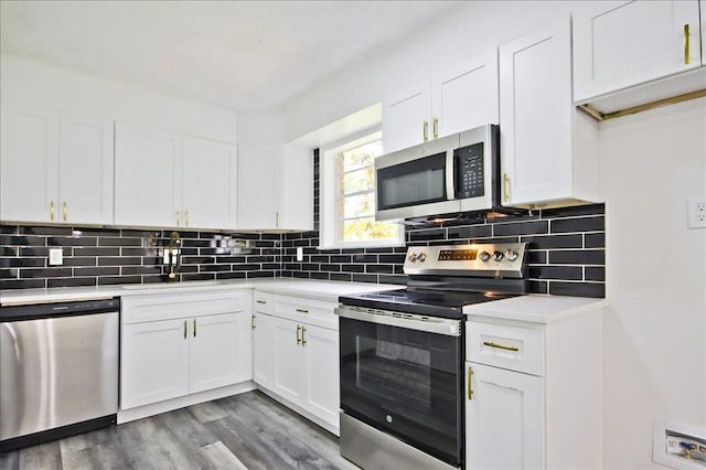 kitchen with wood finished floors, light countertops, white cabinets, backsplash, and stainless steel appliances