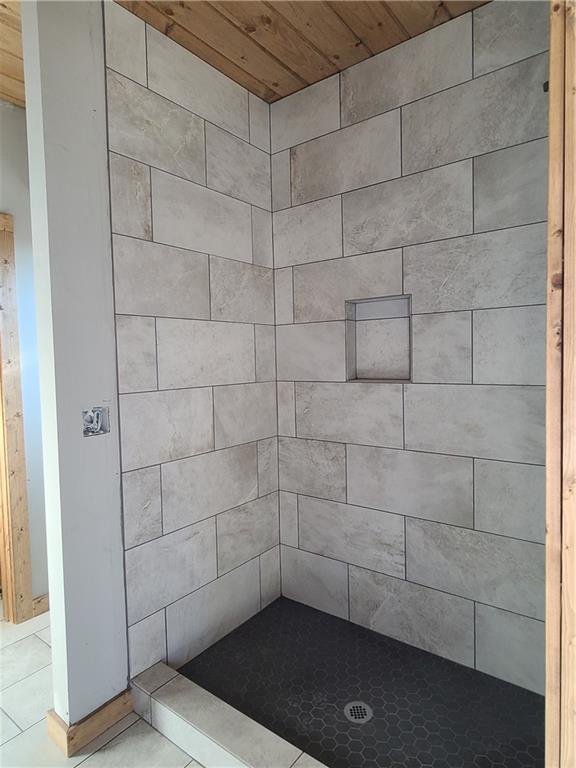 bathroom with a tile shower and tile patterned floors