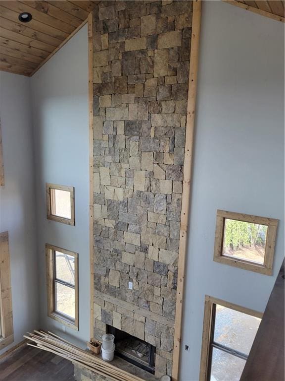 details featuring wooden ceiling, a stone fireplace, and wood finished floors