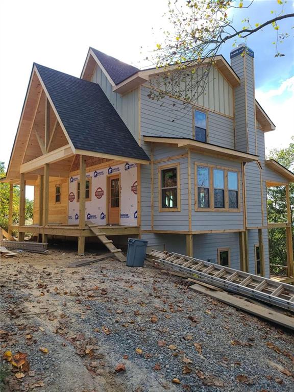 rear view of property featuring a chimney, board and batten siding, and roof with shingles