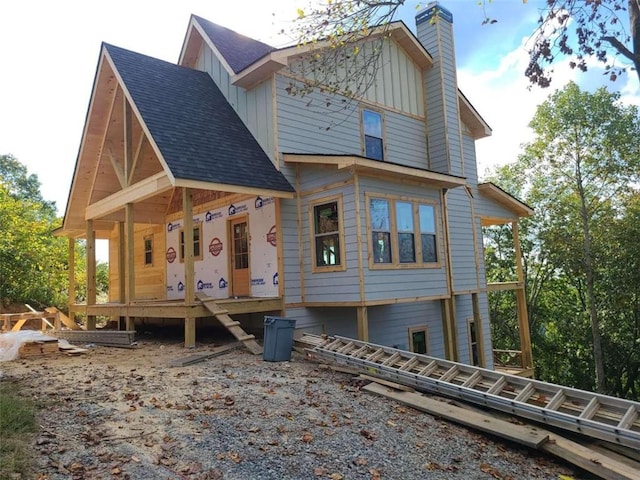 back of house with a chimney, board and batten siding, and roof with shingles