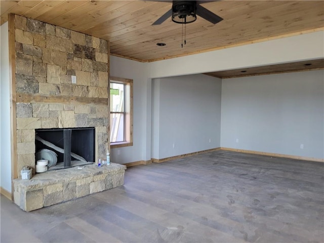 unfurnished living room featuring baseboards, wooden ceiling, ceiling fan, wood finished floors, and a stone fireplace