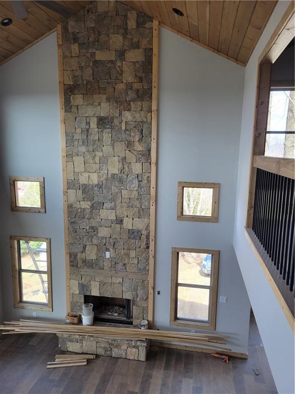 unfurnished living room featuring high vaulted ceiling, a fireplace, wood finished floors, wood ceiling, and a healthy amount of sunlight