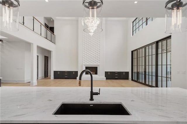 kitchen with sink, light stone countertops, light hardwood / wood-style flooring, and a fireplace