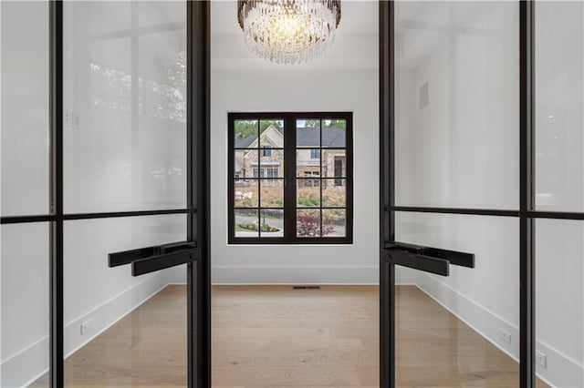 interior space with a notable chandelier, french doors, and wood-type flooring