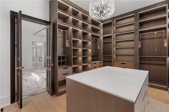 walk in closet with a chandelier and light hardwood / wood-style flooring