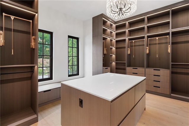 spacious closet with an inviting chandelier and light wood-type flooring