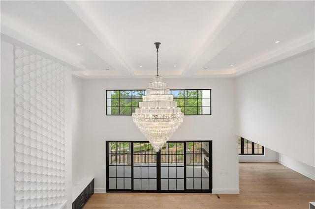 interior space featuring a notable chandelier, a wealth of natural light, beam ceiling, and light wood-type flooring