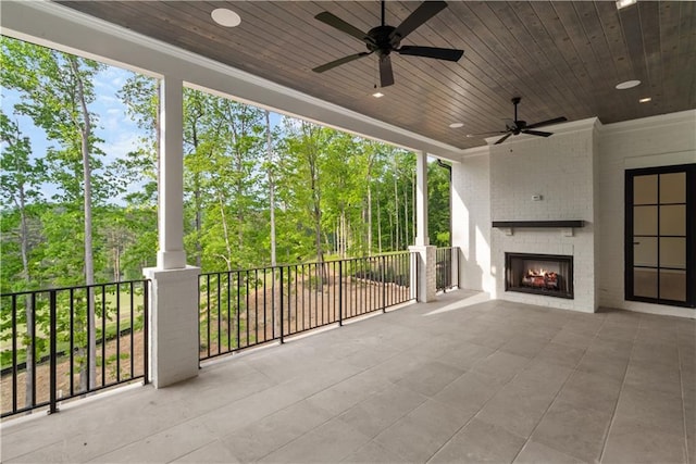 view of patio featuring ceiling fan and a large fireplace