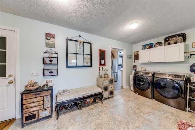 washroom featuring cabinets, a textured ceiling, and washing machine and dryer