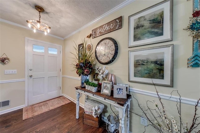 entrance foyer with a notable chandelier, a textured ceiling, ornamental molding, and dark hardwood / wood-style flooring