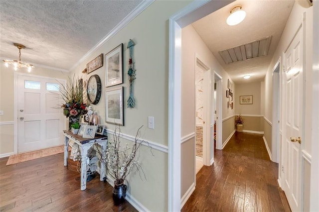 entrance foyer featuring a notable chandelier, a textured ceiling, crown molding, and dark hardwood / wood-style flooring