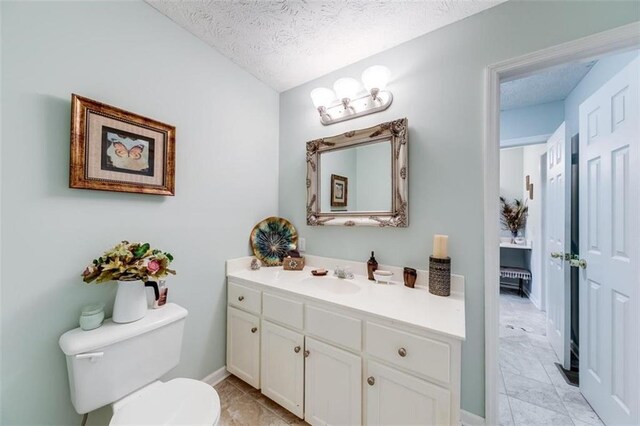 bathroom with a textured ceiling, vanity, and toilet