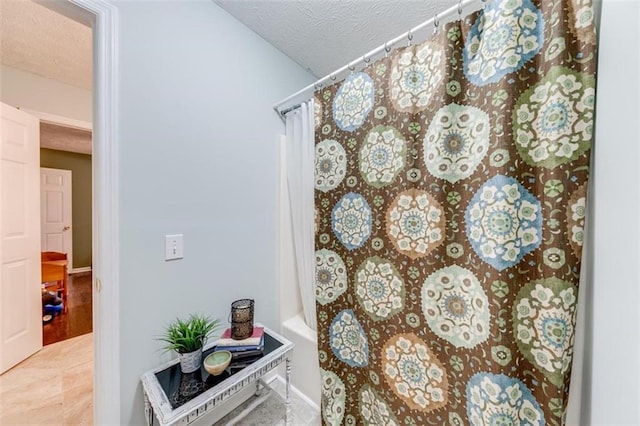 bathroom with a textured ceiling, shower / bath combo, and hardwood / wood-style floors