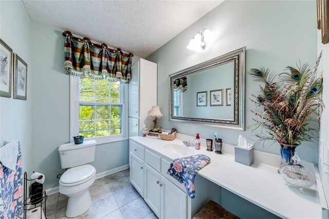 bathroom featuring vanity, toilet, a textured ceiling, and tile patterned floors