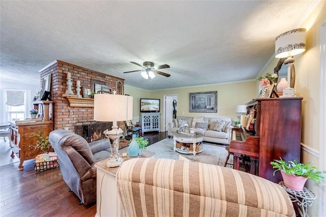 living room featuring a brick fireplace, a textured ceiling, dark hardwood / wood-style floors, and ceiling fan