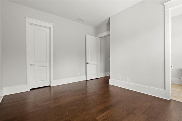 unfurnished bedroom with dark wood-type flooring and baseboards