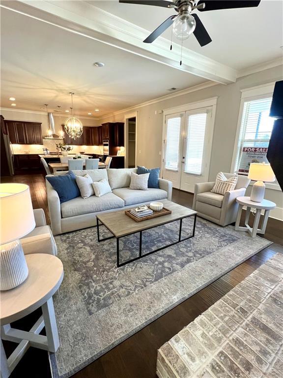 living room featuring ceiling fan with notable chandelier, dark wood-style flooring, crown molding, and recessed lighting