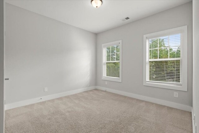 empty room with light carpet, visible vents, and baseboards