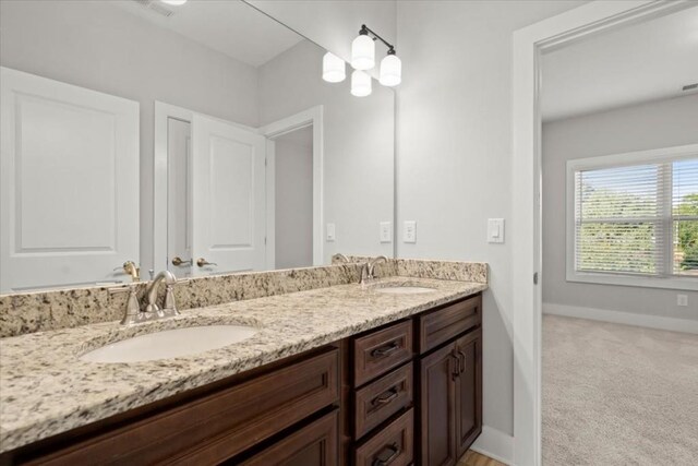 bathroom with a sink, baseboards, and double vanity