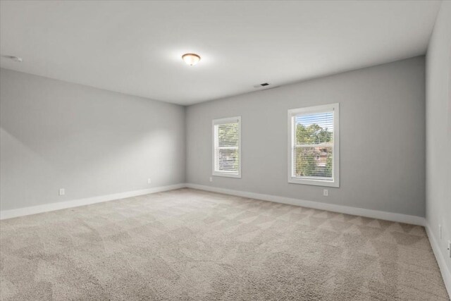 empty room with visible vents, baseboards, and light colored carpet