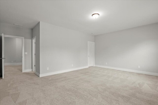 unfurnished room featuring light carpet and baseboards