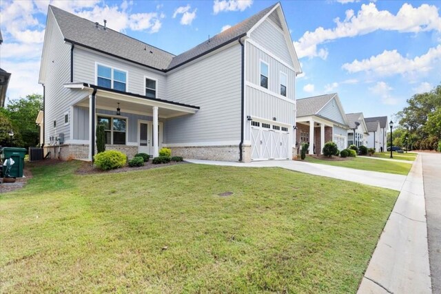 view of front of home featuring central air condition unit, a garage, driveway, board and batten siding, and a front yard