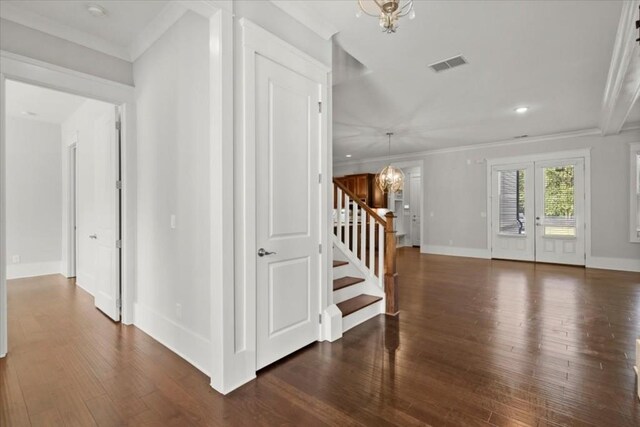 entrance foyer featuring ornamental molding, visible vents, a notable chandelier, and stairway