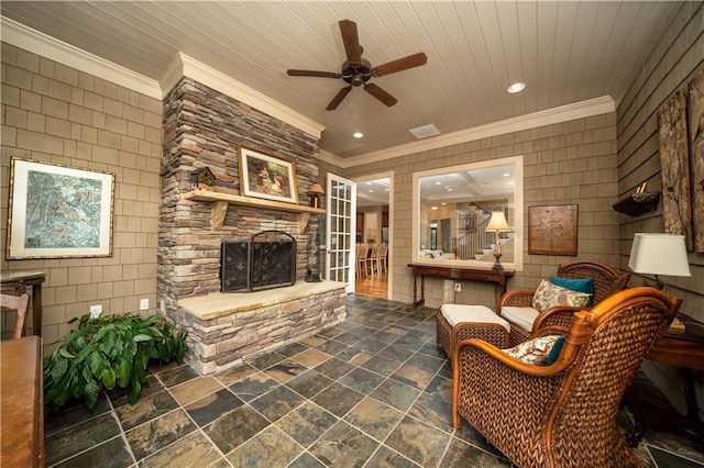 living area with a fireplace, ceiling fan, crown molding, and tile walls