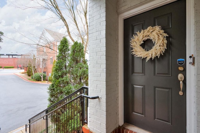 entrance to property with brick siding and a balcony