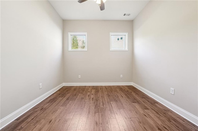 empty room with visible vents, wood-type flooring, baseboards, and a ceiling fan